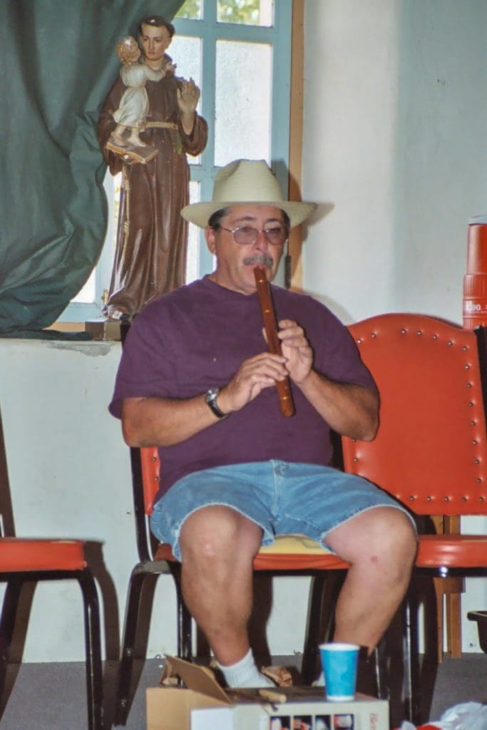 A man playing the flute sitting on the chair