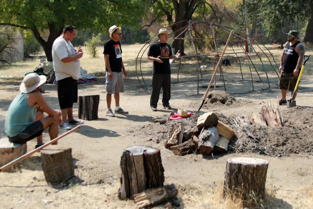 Five men wearing hats arranging bonfire