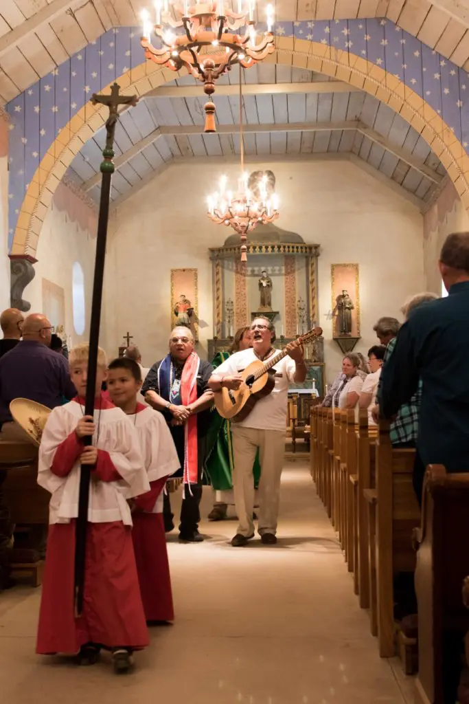 A man playing a guitar in front of others in the church