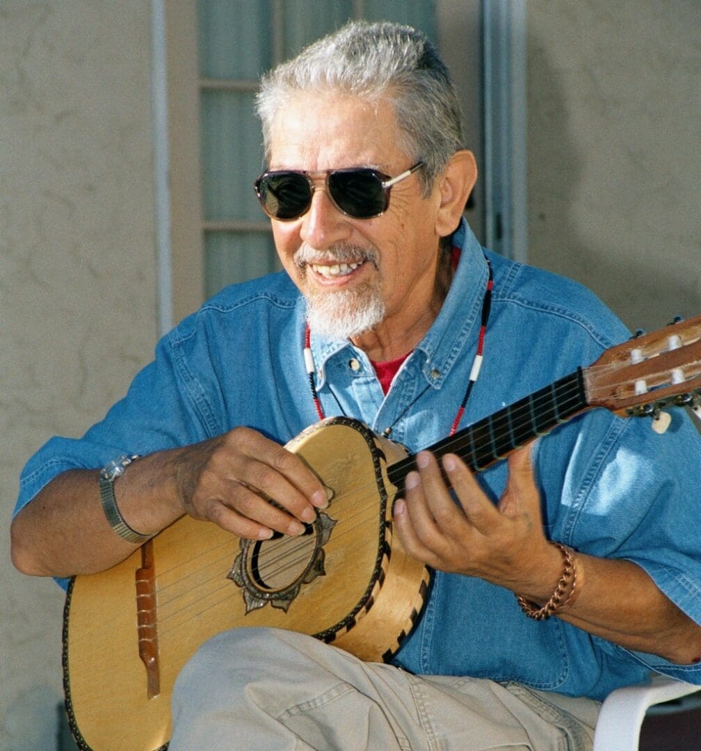 Maestro Jose Montoya wearing sunglasses playing guitar